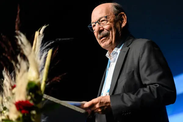 Aelterer Redner am Mikrofon auf Buehne