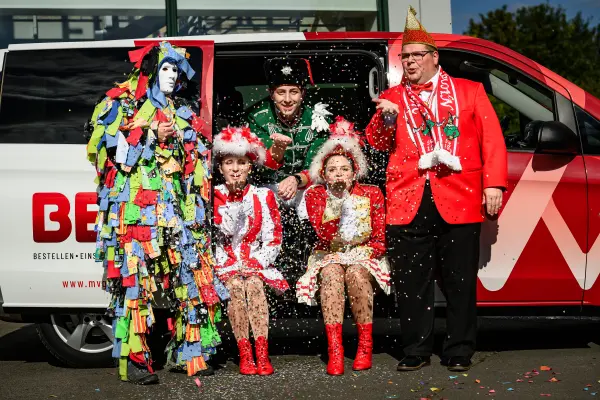 Karnevalsgruppe mit Konfetti vor BEA-Van